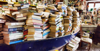Piles of used books within a blue boat in a bookshop