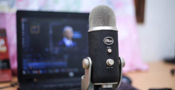 Podcast microphone in front of laptop display of video editing software